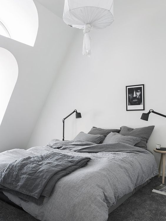 a cozy attic Nordic bedroom with arched windows, a bed, table .