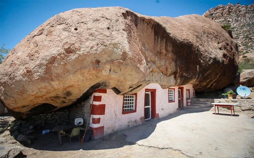 Home built beneath a huge rock in the desert becomes a tourist .