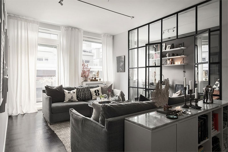 Black and white apartment with home office behind glass partition .