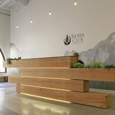 A plant-filled stack of timber beams forms the reception desk of .